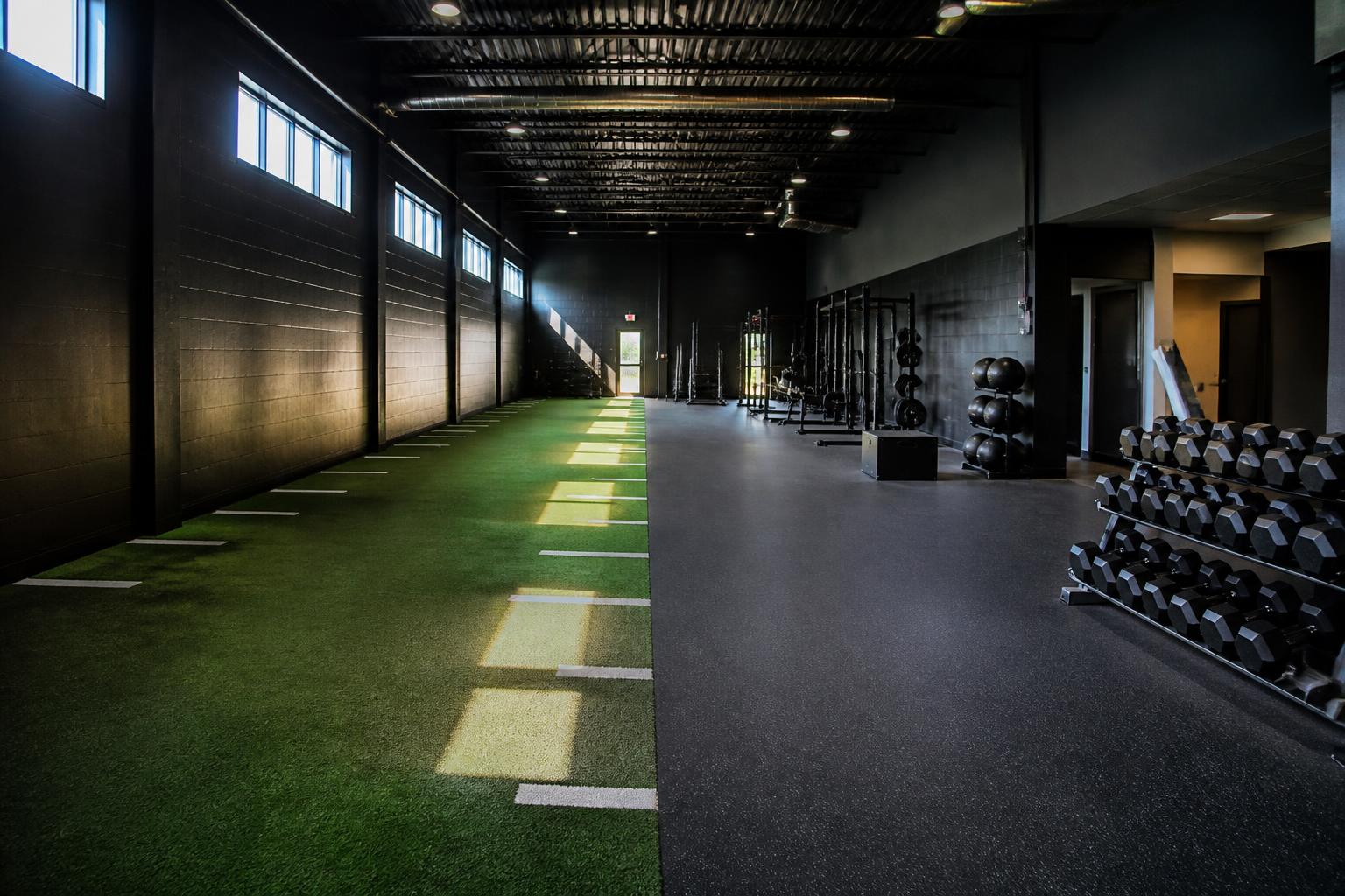 Renovated training floor with turf sprint lane and strength equipment